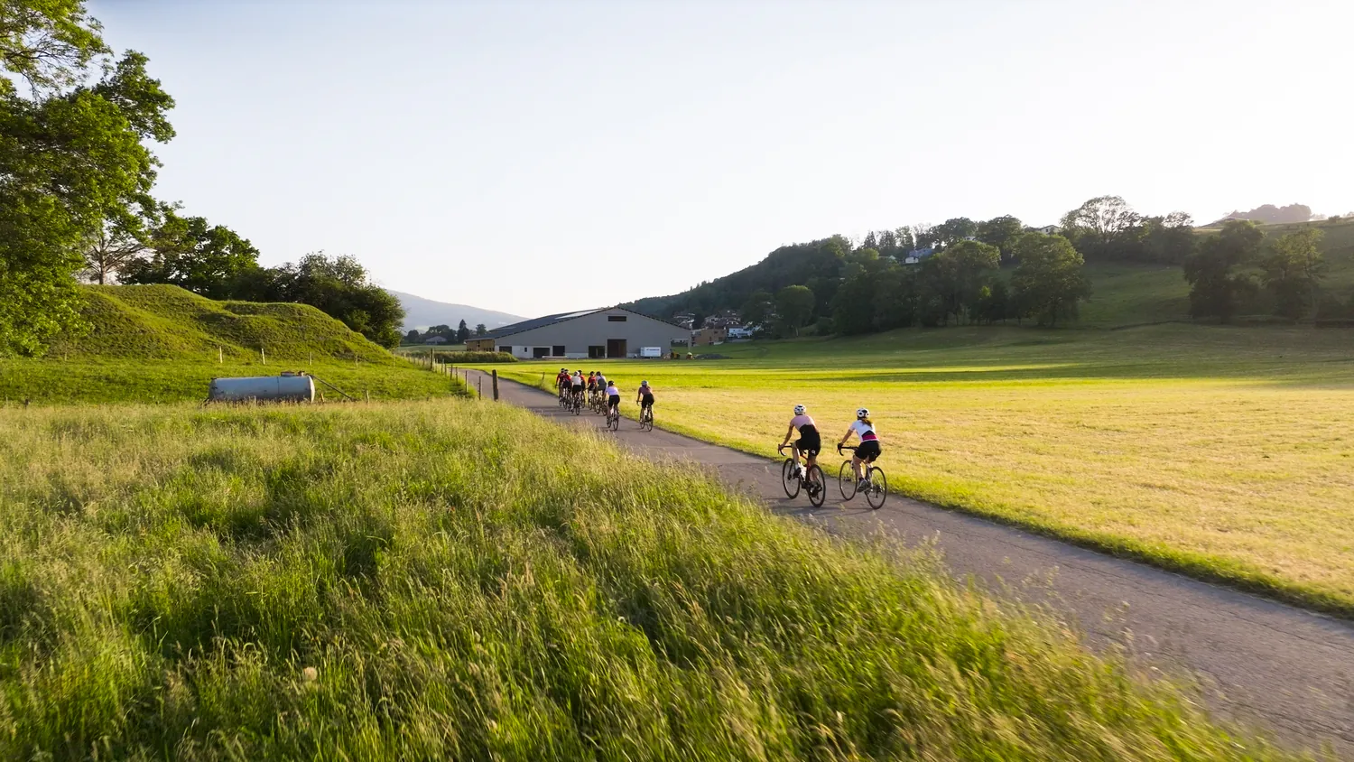 Groupe de cyclistes du Social Ride à vélo dans la campagne de Bulle au coucher du soleil